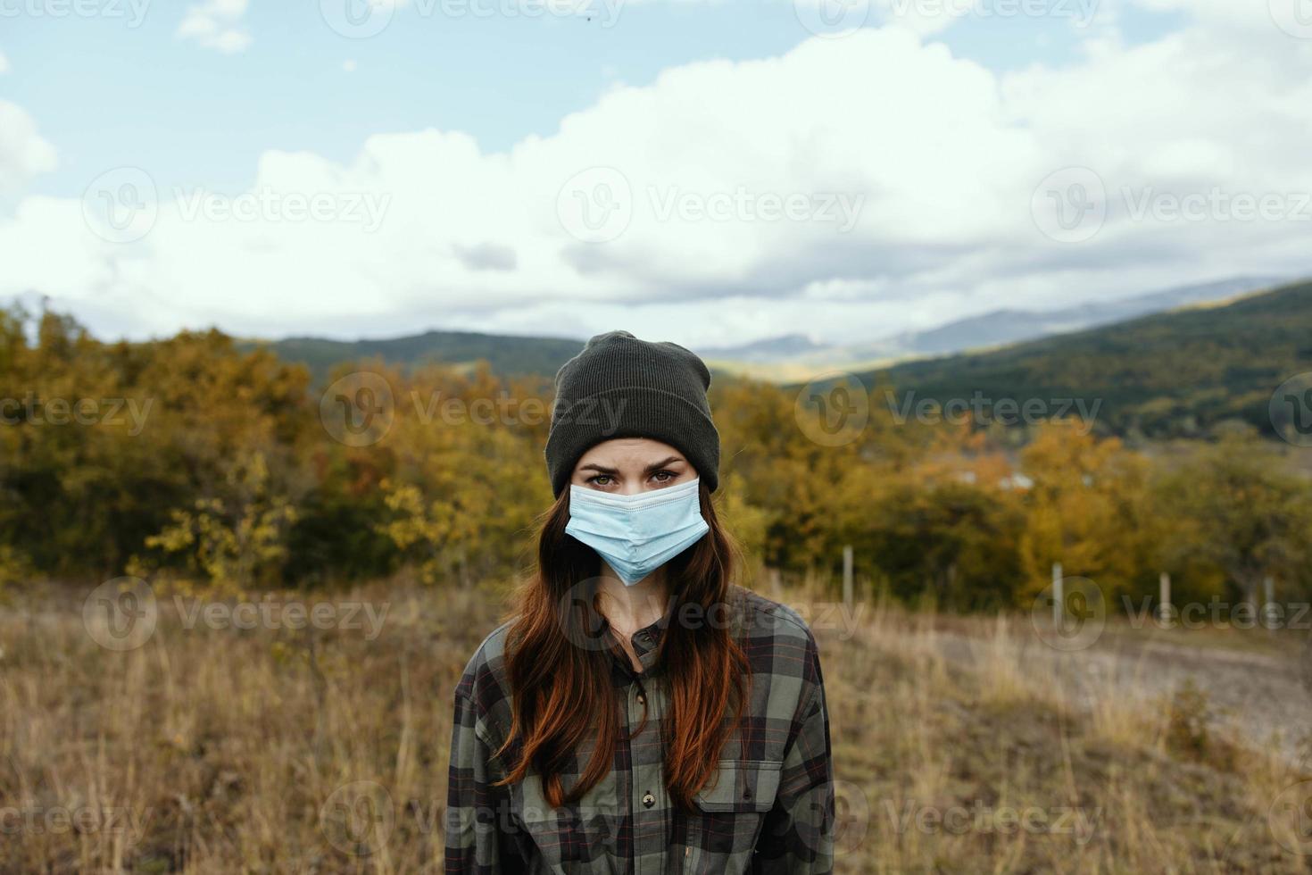 Traveler in a medical mask and a strict look at nature autumn mountains photo