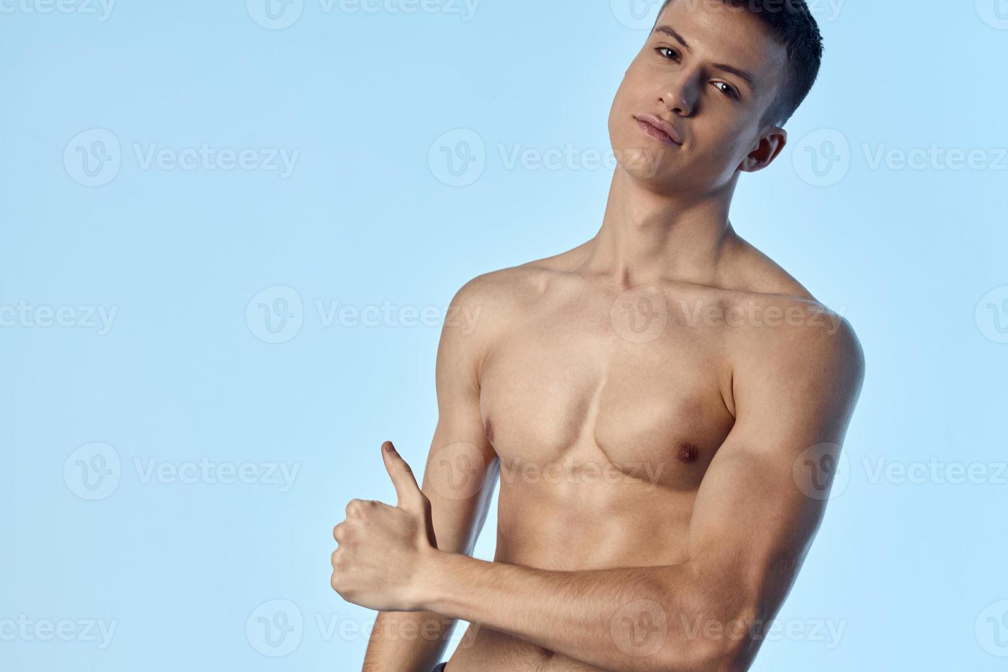 athlete on a blue background shows thumb Copy Space naked torso biceps bodybuilder photo