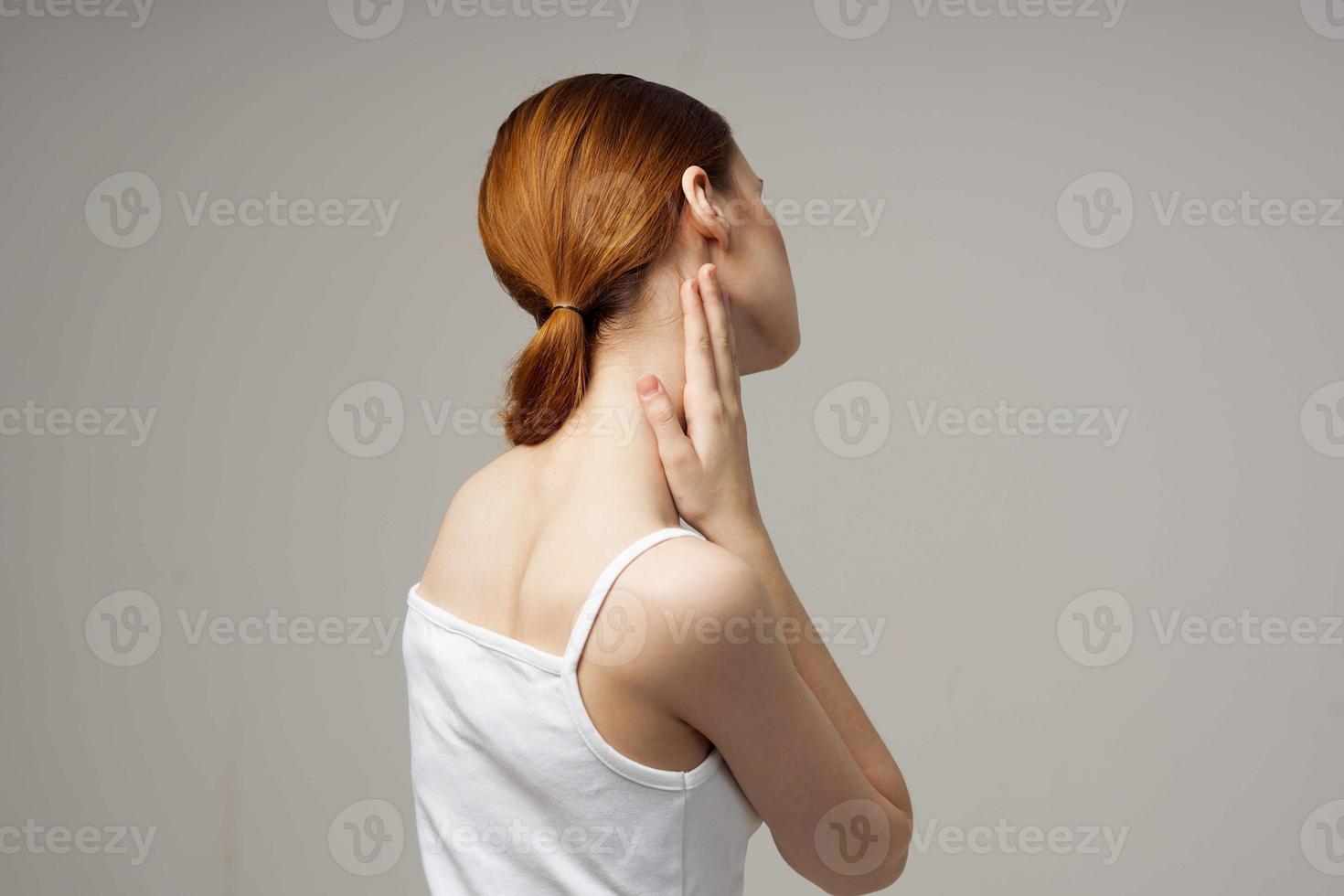 woman in white t-shirt holding on to the neck health problems joint light background photo