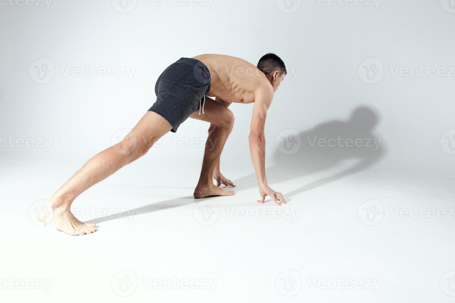 sports guy in shorts in a bright room leaning down photo