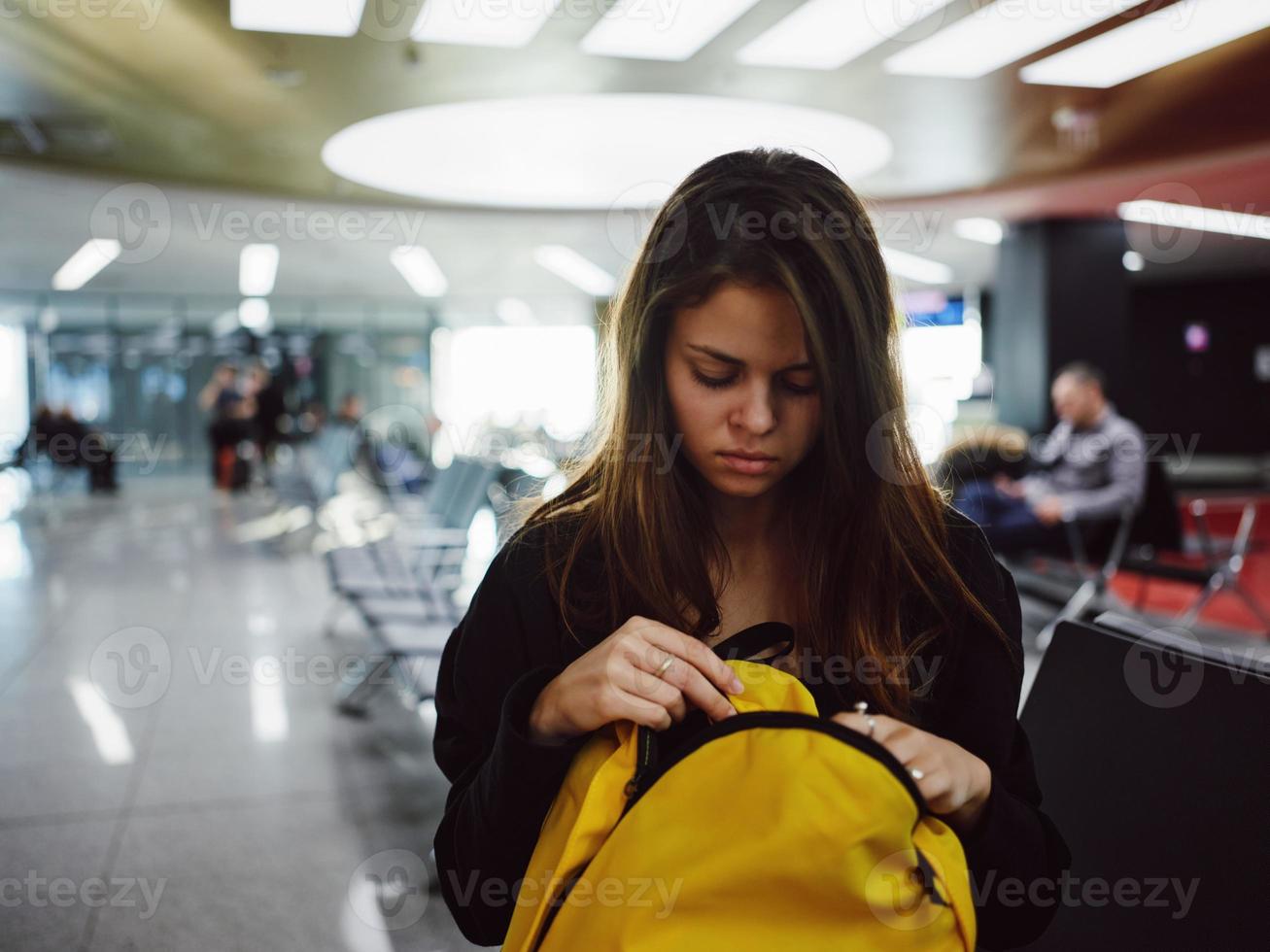 woman sitting at the airport with yellow backpack waiting photo