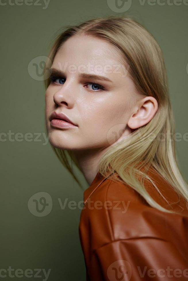 Headshot portrait of stylish confident professional blonde model looks at camera. Closeup shot in studio on over olive green background photo
