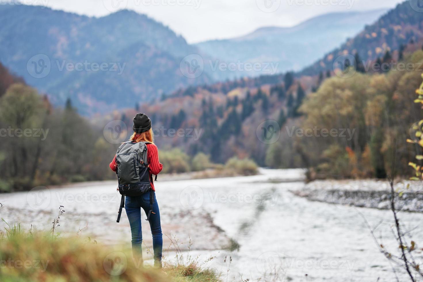 woman in a red sweater with a backpack in the mountains on nature near the river pond lake photo