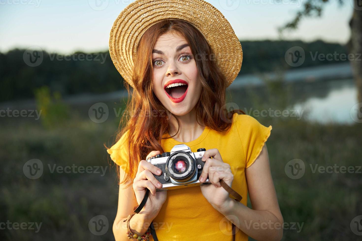 Surprised woman with camera yellow t-shirt hat summer nature lifestyle photo