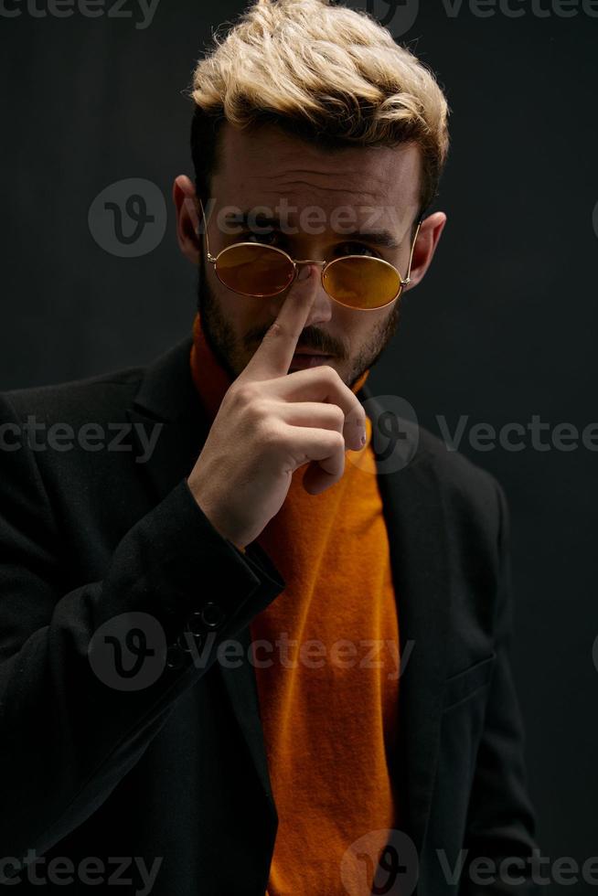 stylish man in orange sweater straightens glasses on his face photo