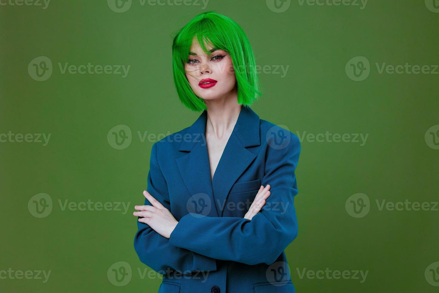 Portrait of a charming lady wearing a green wig blue jacket posing green background unaltered photo