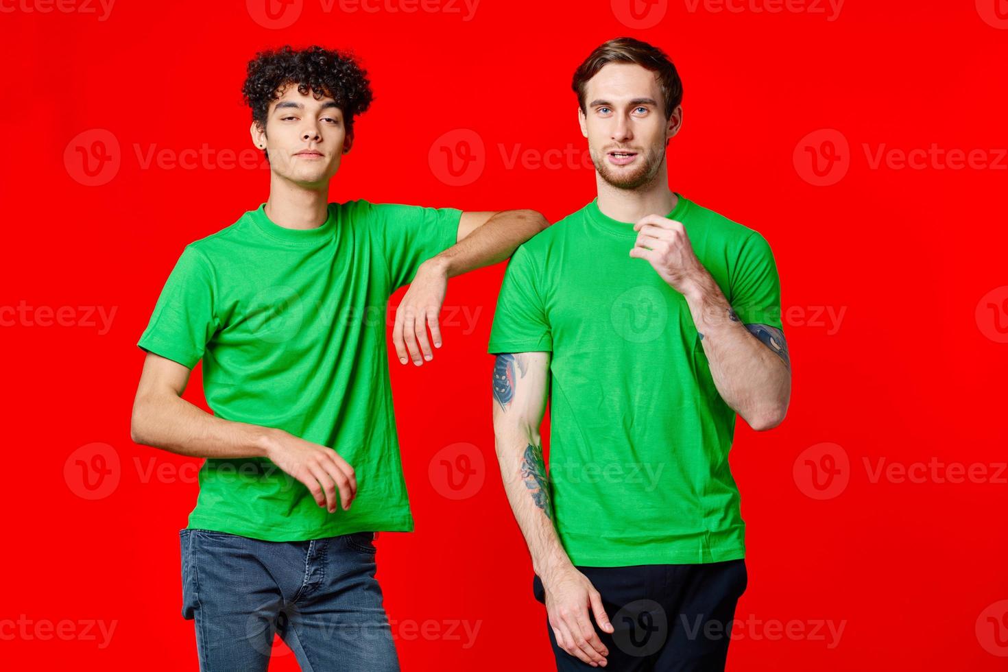 Two cheerful friends in green t-shirts joy of communication red background photo