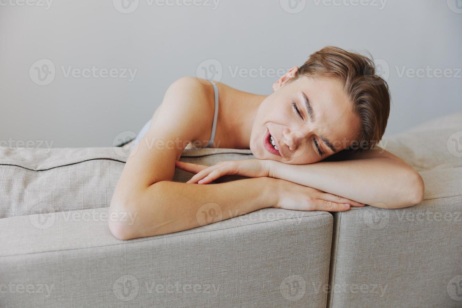 contento mujer sonrisa acostado a hogar en el sofá relajante en un fin de semana a hogar con un corto Corte de pelo pelo sin filtros en un blanco fondo, gratis Copiar espacio foto