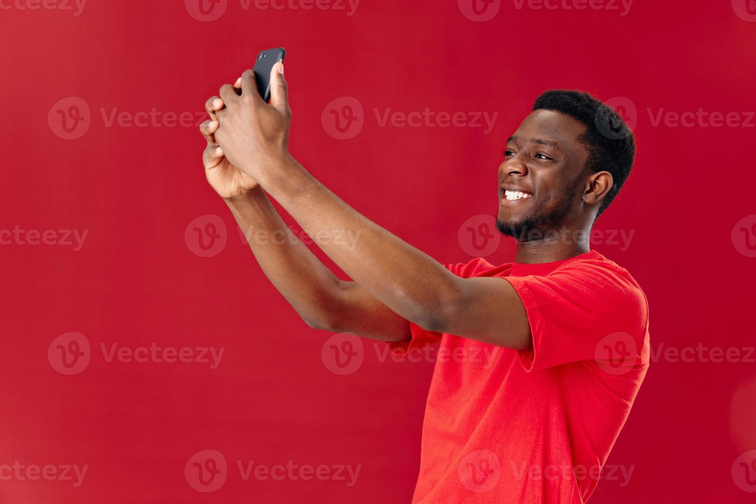 alegre hombre de africano apariencia participación teléfono encima su cabeza comunicación aislado antecedentes foto