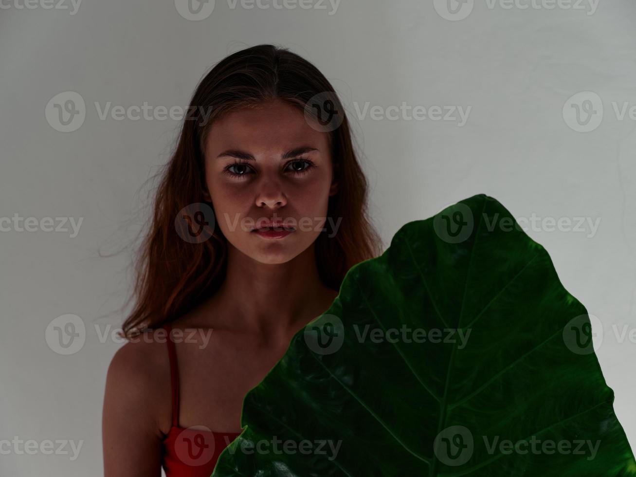 pretty woman serious expression red swimsuit palm leaf close-up photo