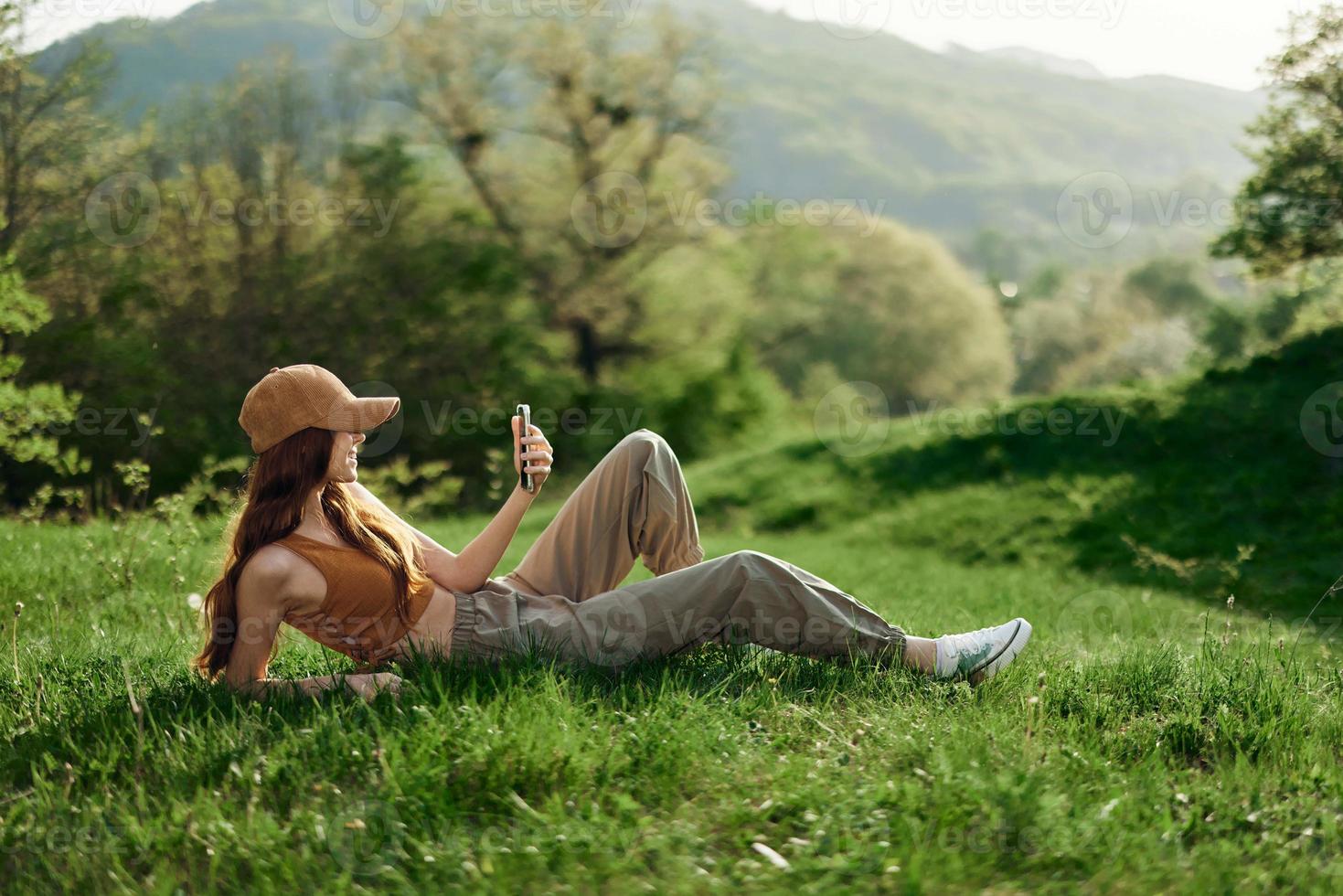 Blogger with phone working in park on grass by tree, freelancer lifestyle photo