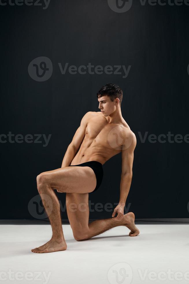 sporty man with a pumped-up naked body posing on his knee photo