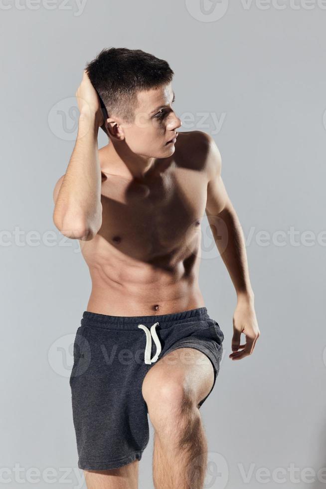 sport man in shorts doing exercise leaning forward on gray background cropped view photo