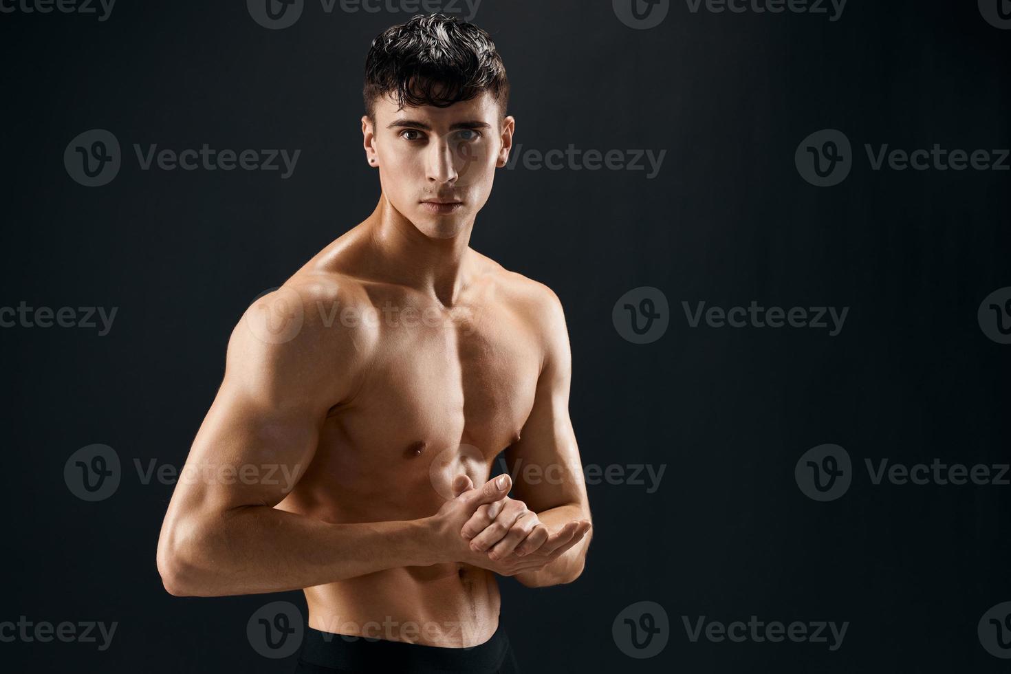 man with muscular muscle body posing against dark background cropped view photo