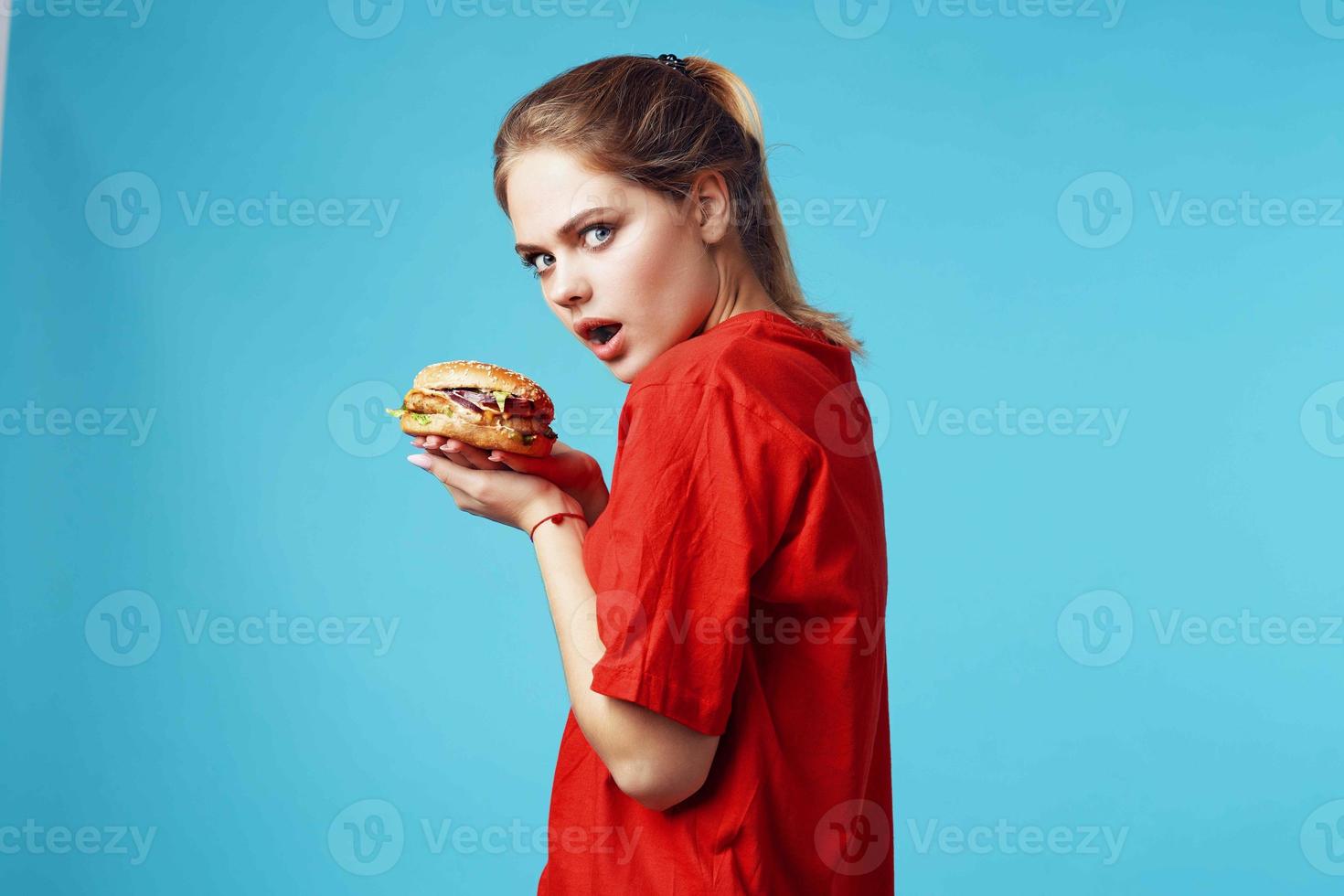cheerful woman in red t-shirt hamburger in hands fast food blue background photo