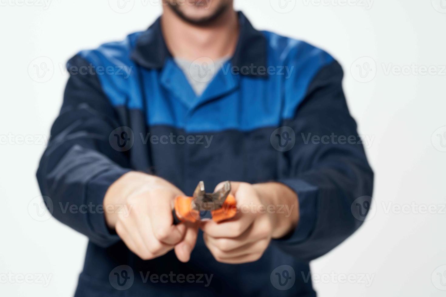 man in construction uniform with pliers in hands repair service photo