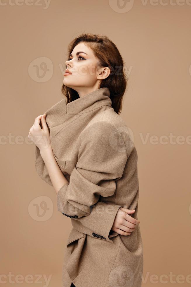 woman in coat touches collar with hands side view photo