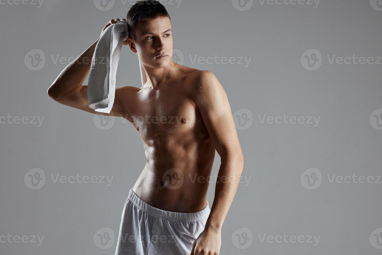 athletic man in white shorts towel in hands posing inflated torso isolated background photo