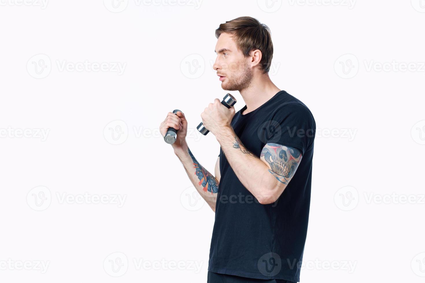 atleta en un negro camiseta son comprometido en aptitud en un blanco antecedentes adentro y pesas en mano foto