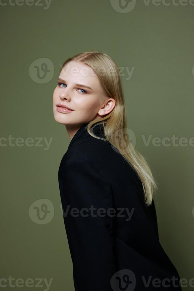 Attractive beautiful bright girl looks into the camera posing in the studio in a suit on a green background photo