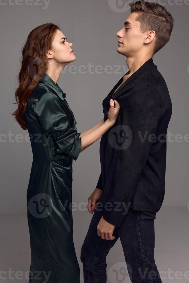 A woman looks indignantly at a young man in a suit on a gray background photo