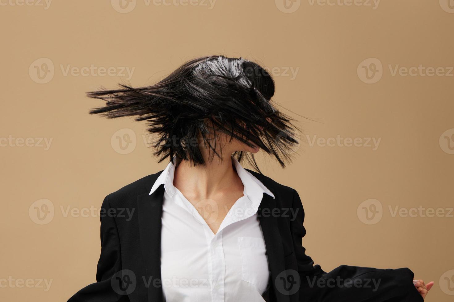 Happy dancing adorable brunet lady in classic suit throws head with flying hair posing isolated on pastel beige studio background. Copy space Banner Offer. Pulp Fiction concept. Fashion Cinema photo