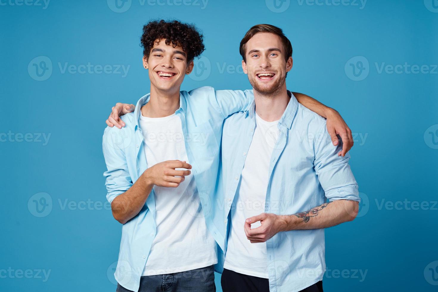 man with curly hair hugs his friend on blue background fun cropped view photo