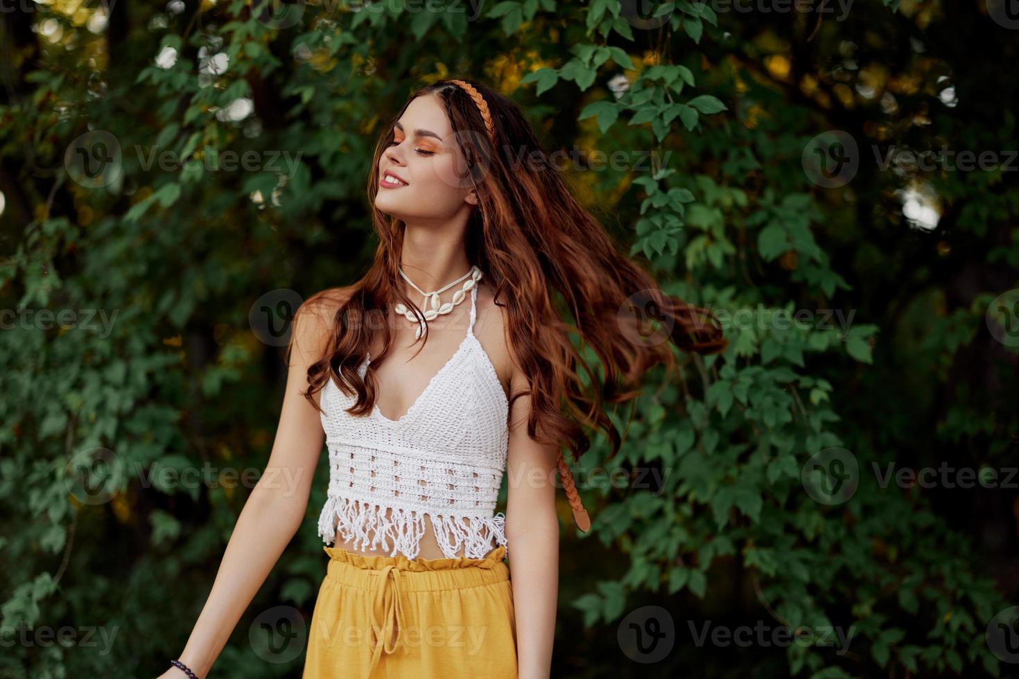 A woman in eco-friendly clothing in a hippie look dances in nature in the park and smiles at the world. The concept of harmony with the body and the surrounding nature photo