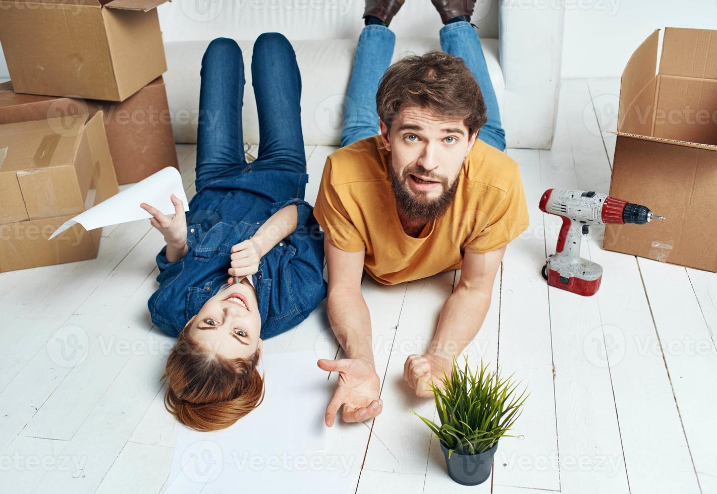 To women men on a wooden floor with boxes and a flower in a pot photo