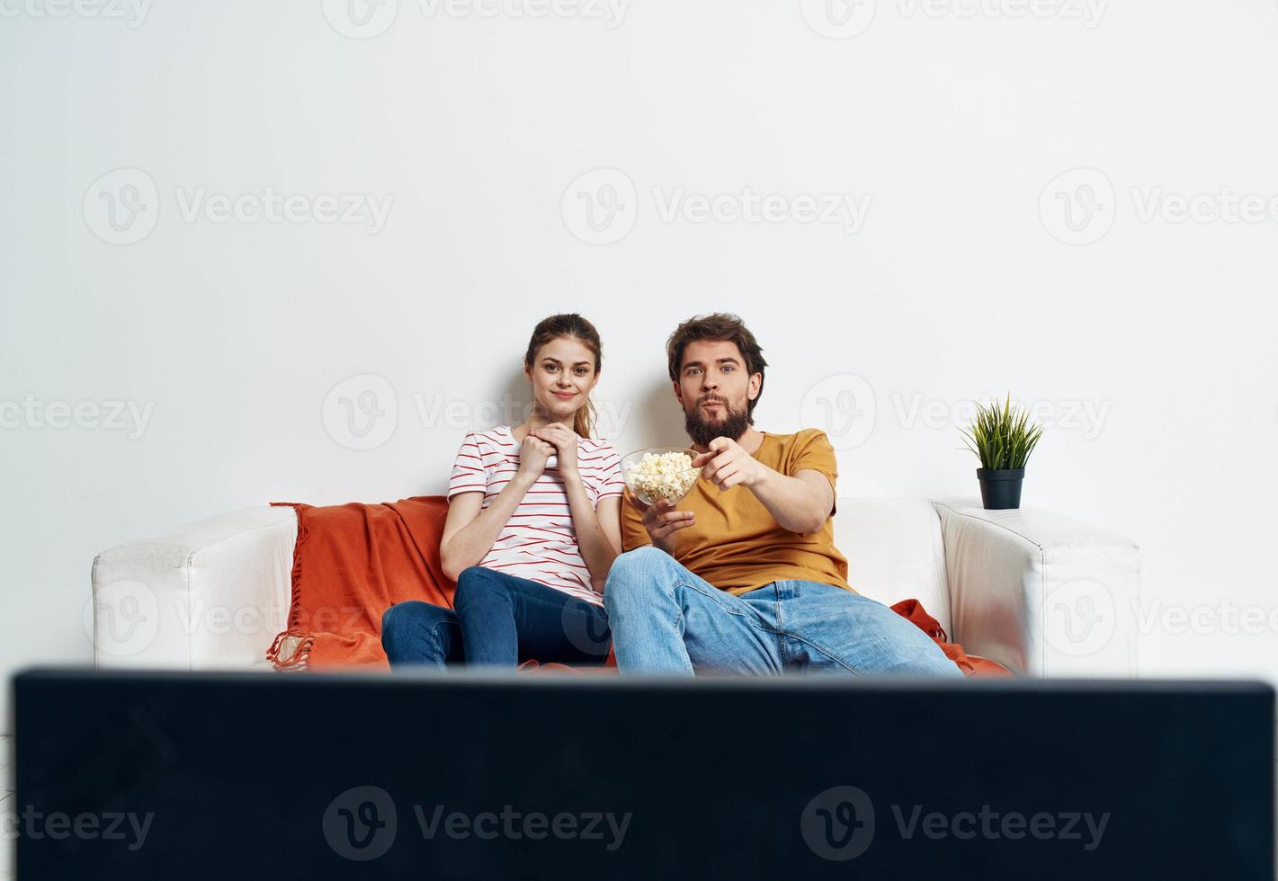 A man and a woman on the couch watching the TV indoors watching the show photo