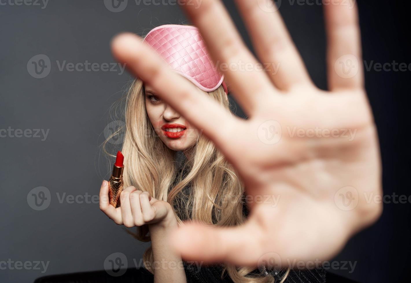 drunk woman with bright makeup gesturing with her hands palm gray background photo