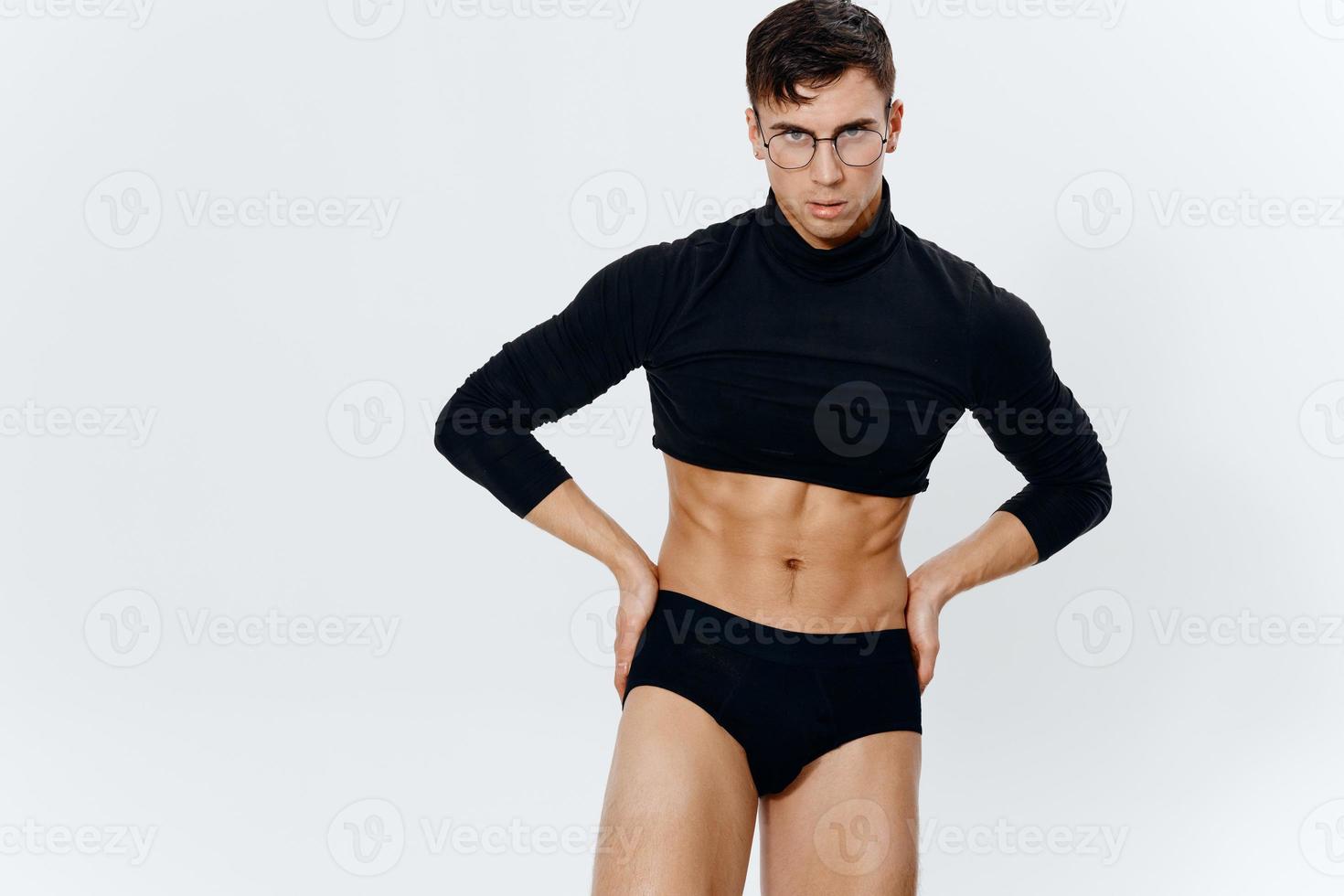 sporty man with a pumped-up torso in a sweater holds his hand on his belt on a light background photo