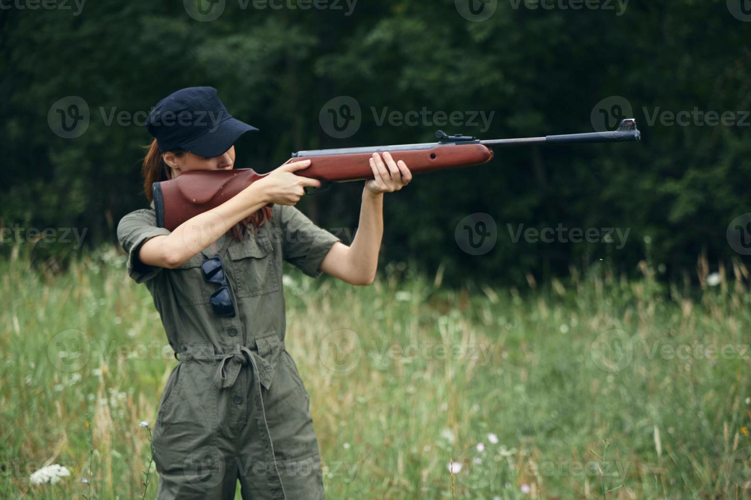 mujer en naturaleza con un pistola en su manos, puntería un verde mono armas foto