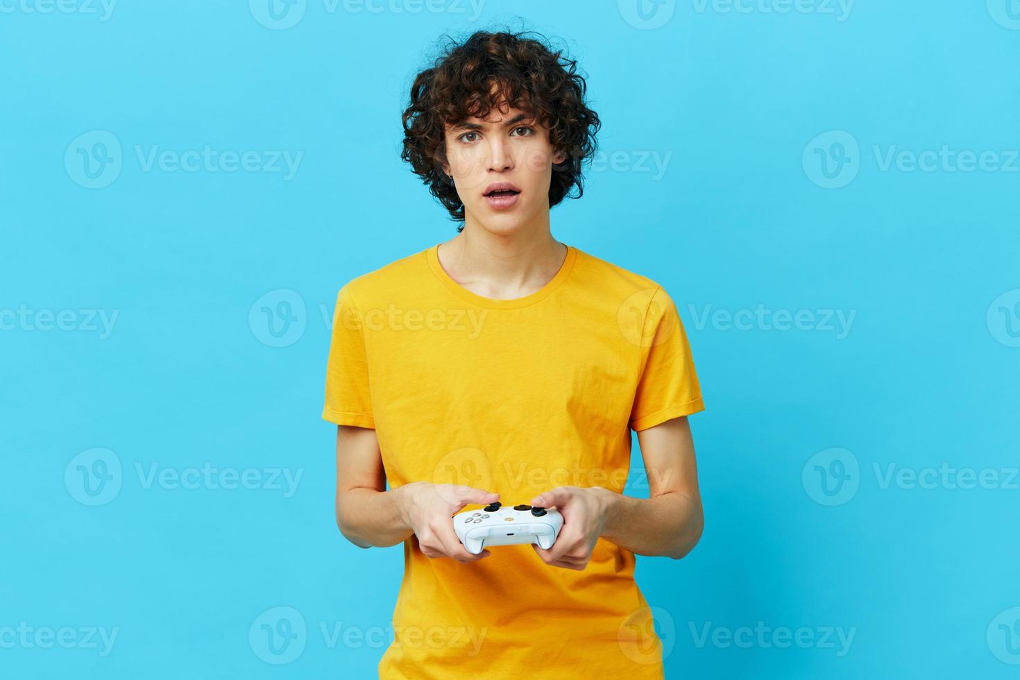 curly guy yellow T-shirt with joystick video games blue background photo