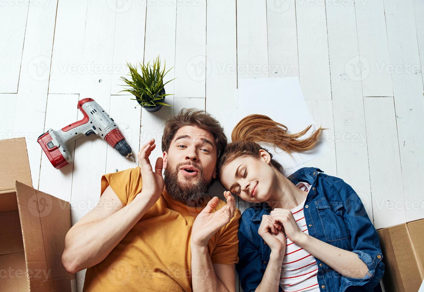 Moving to an apartment a man and a woman lie on the floor and a flower in a pot photo