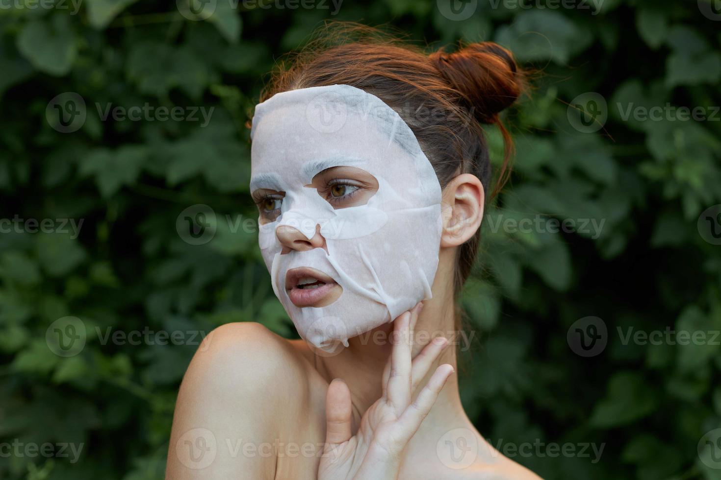 Portrait of a girl face mask Touch your face and look away skin care bushes in the background photo