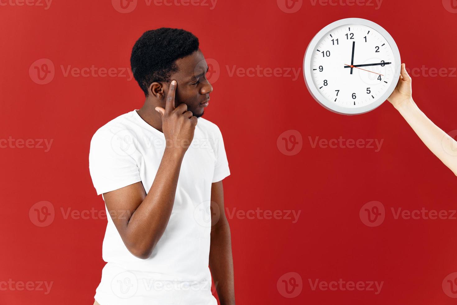 man next to clock in white t-shirt cropped view photo