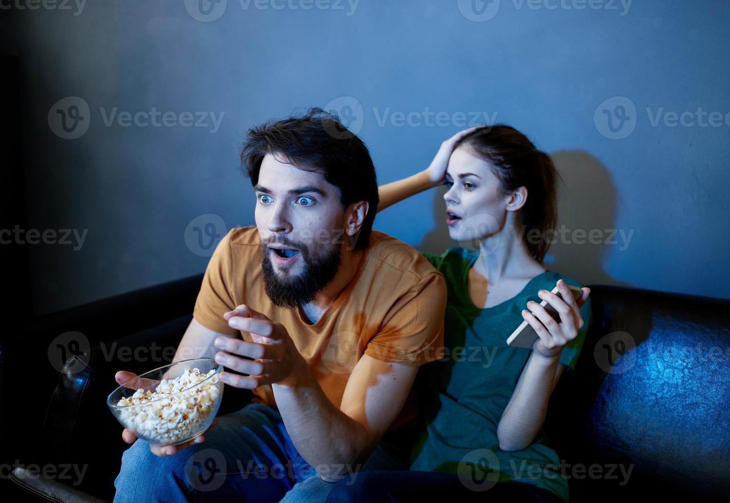 frightened woman and man watching a movie in the evening in front of tv on the couch photo