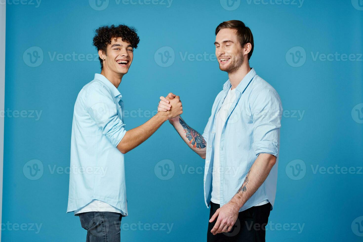 Happy friends in identical shirts shake hands on a blue background communication photo