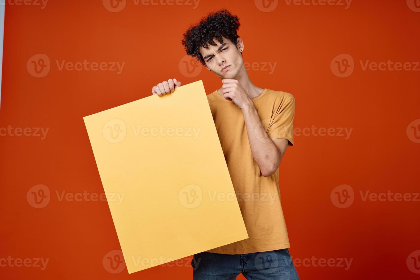 guy with curly hair yellow poster in hands studio advertising Copy Space photo