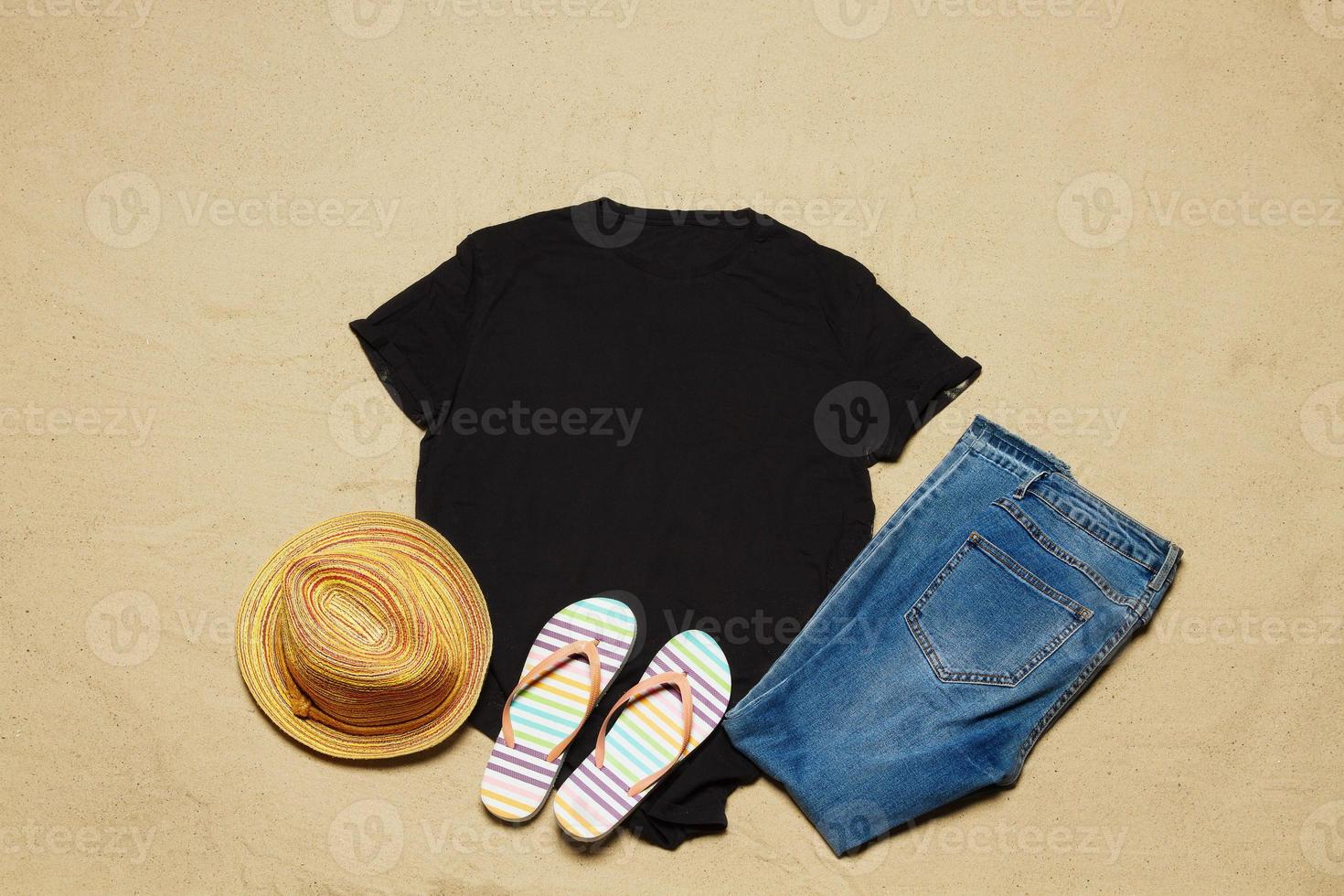 Sand beach texture background. Mockup black summer t-shirt copy space. No wrinkles. Blank template shirt Top view. Summertime clothing. Flat-lay closeup tshirt on seashore. Beachtime holidays photo