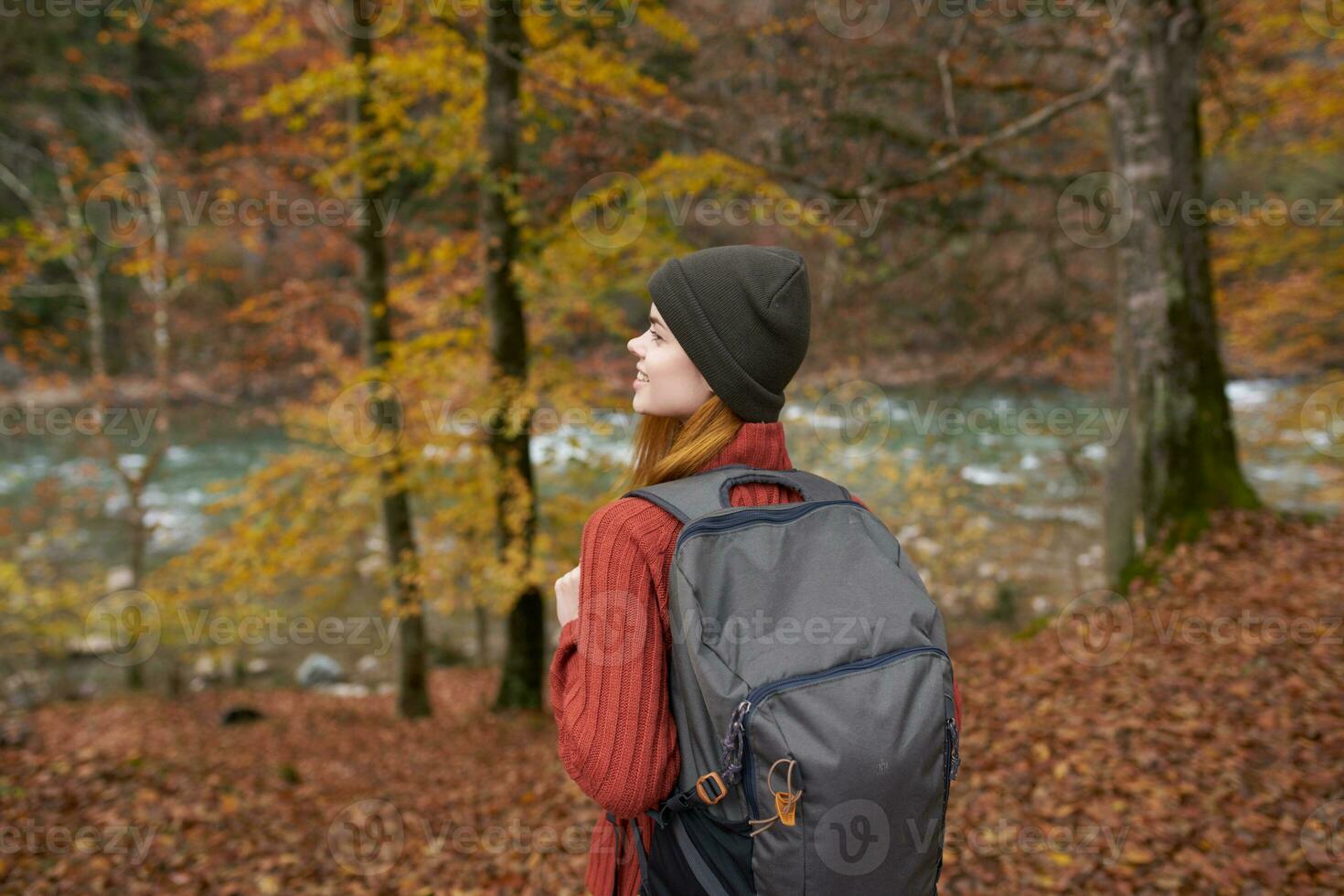 traveler with a backpack and in a gray hat in the autumn forest fallen leaves trees river model photo