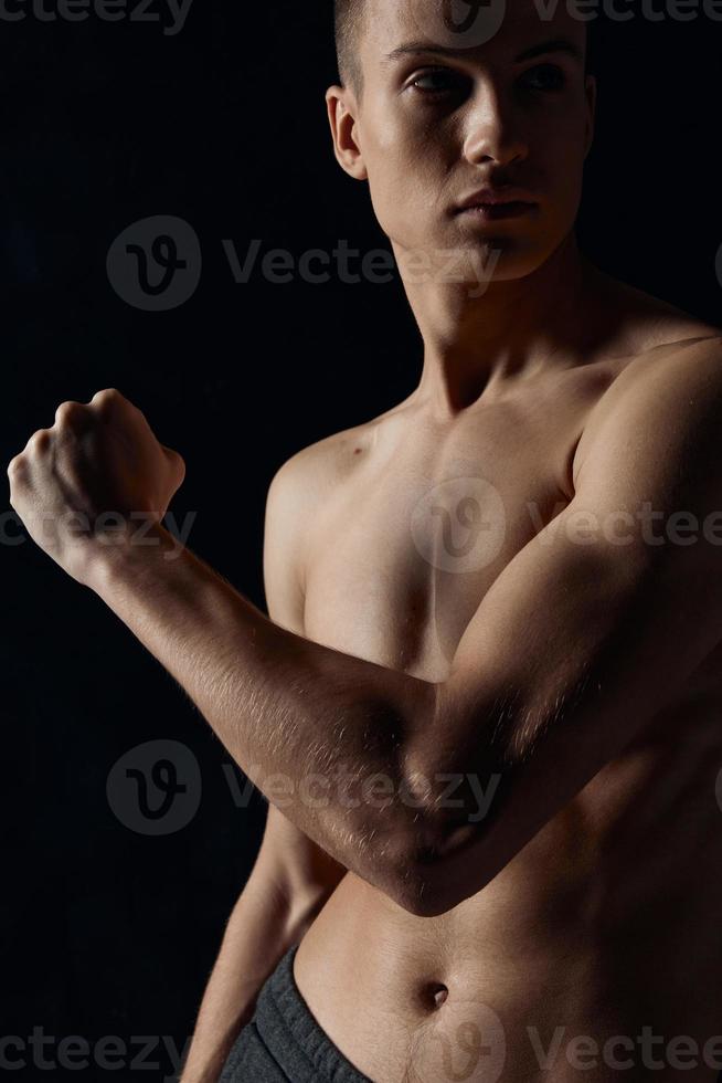 sexy bodybuilder with naked torso on black background looking to the side photo