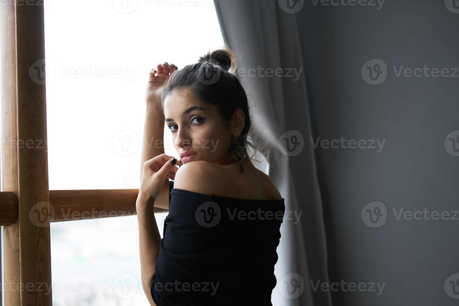 brunette in a black dress near the window posing elegant style photo