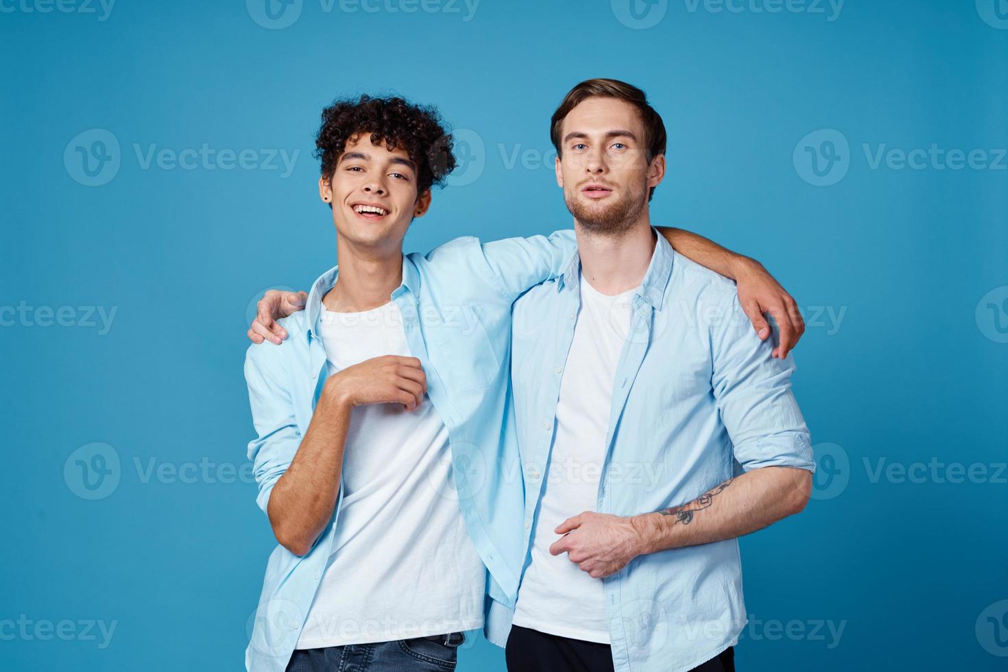 young men in blue shirts hugging on isolated background friends fun photo
