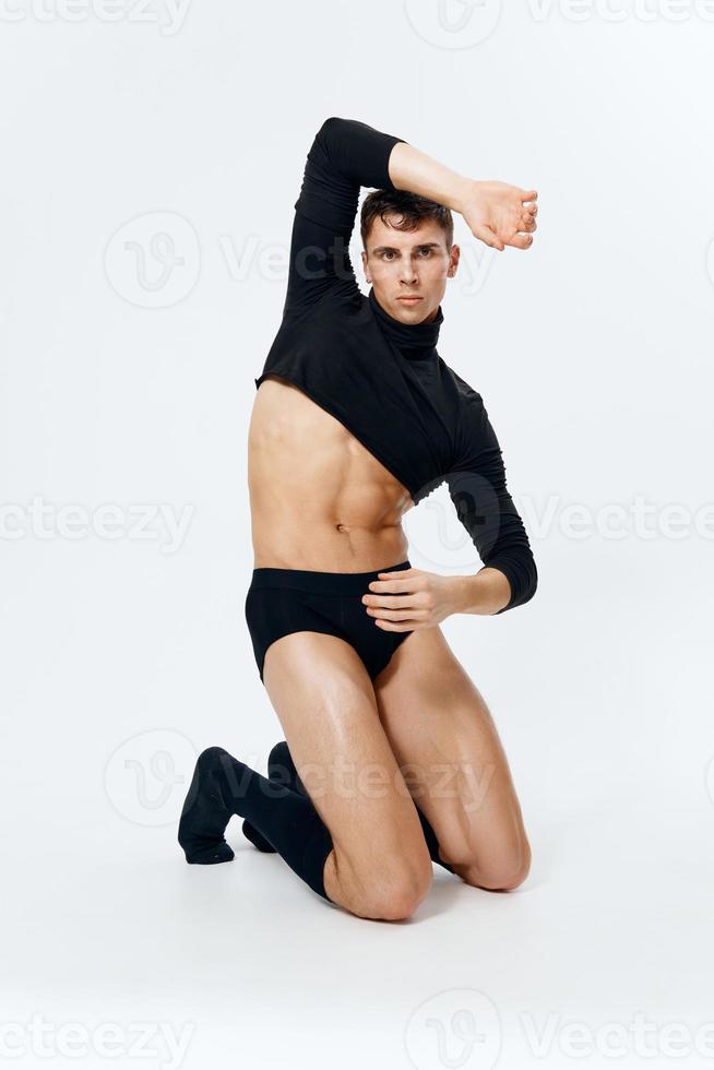 sexy man with an athletic physique kneels on a light background photo
