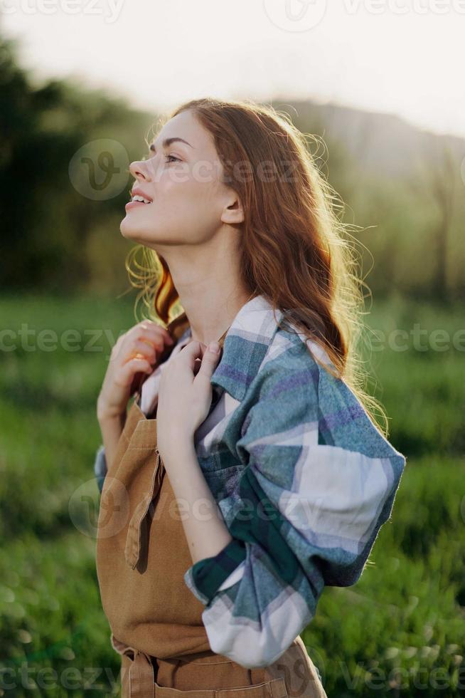 Portrait of a young girl on a summer day in the rays of the setting sun with a beautiful smile, dressed as a farmer and gardener photo