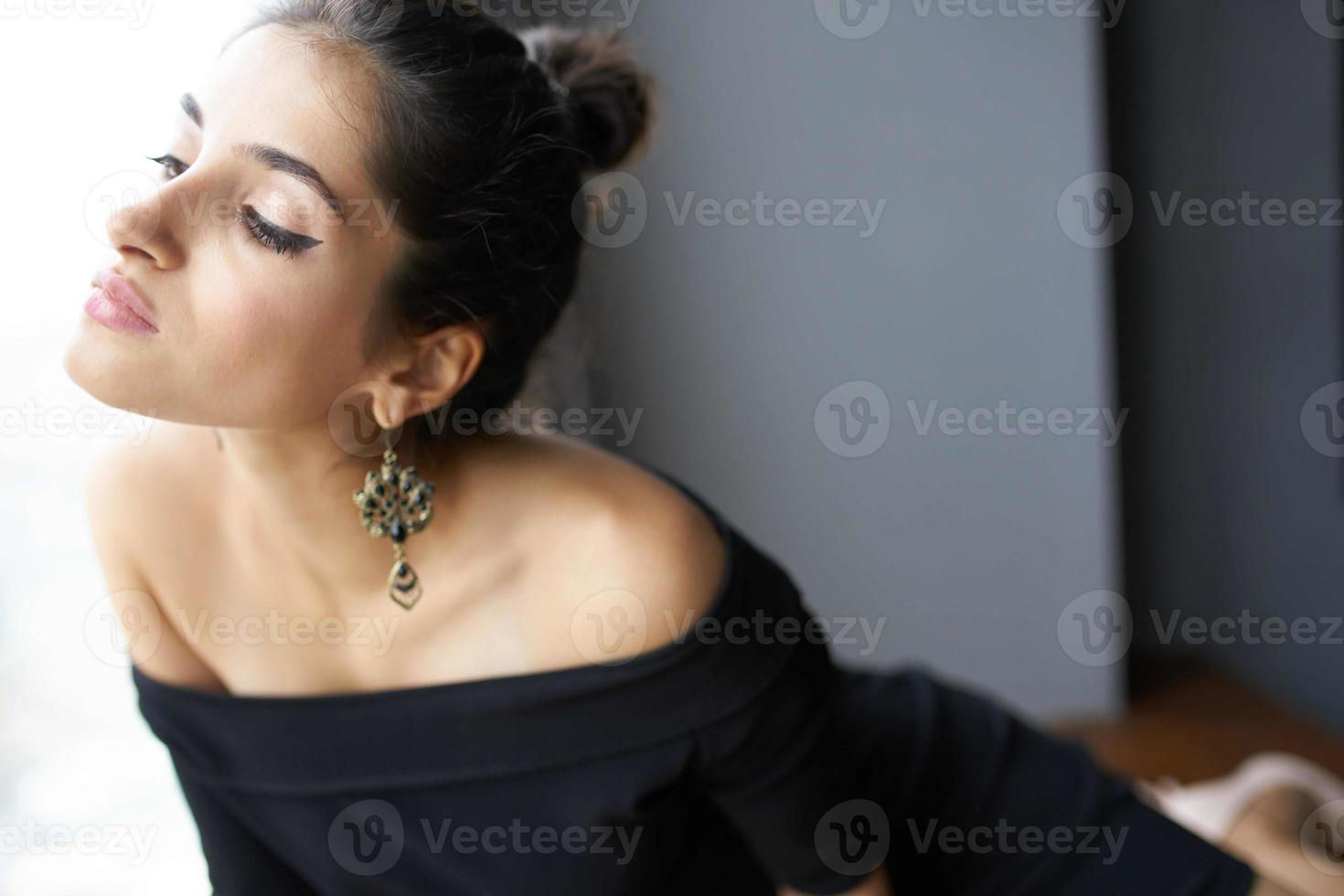 hermosa mujer en un negro vestir cerca el ventana posando elegante estilo foto