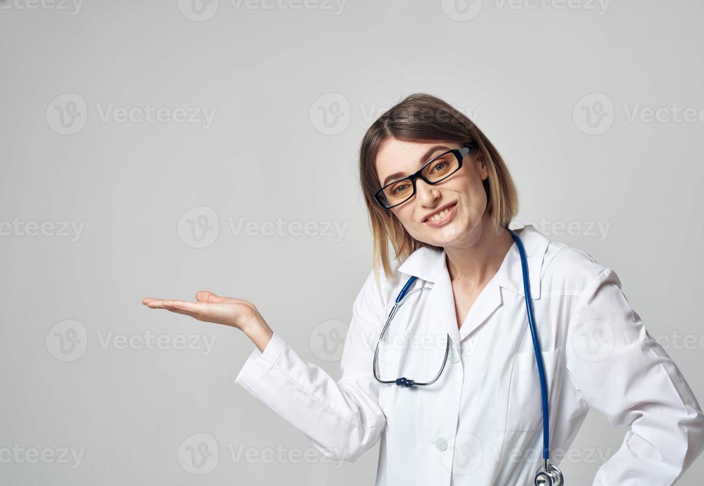 woman nurse in a medical gown gesturing with her hands on a light background copy space photo