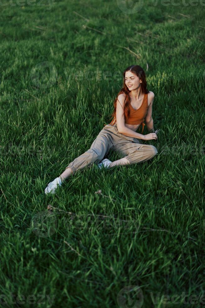 A woman lies on fresh spring green grass in a park without mosquitoes or ticks and enjoys relaxing while watching the sunset. The concept of safe outdoor recreation photo